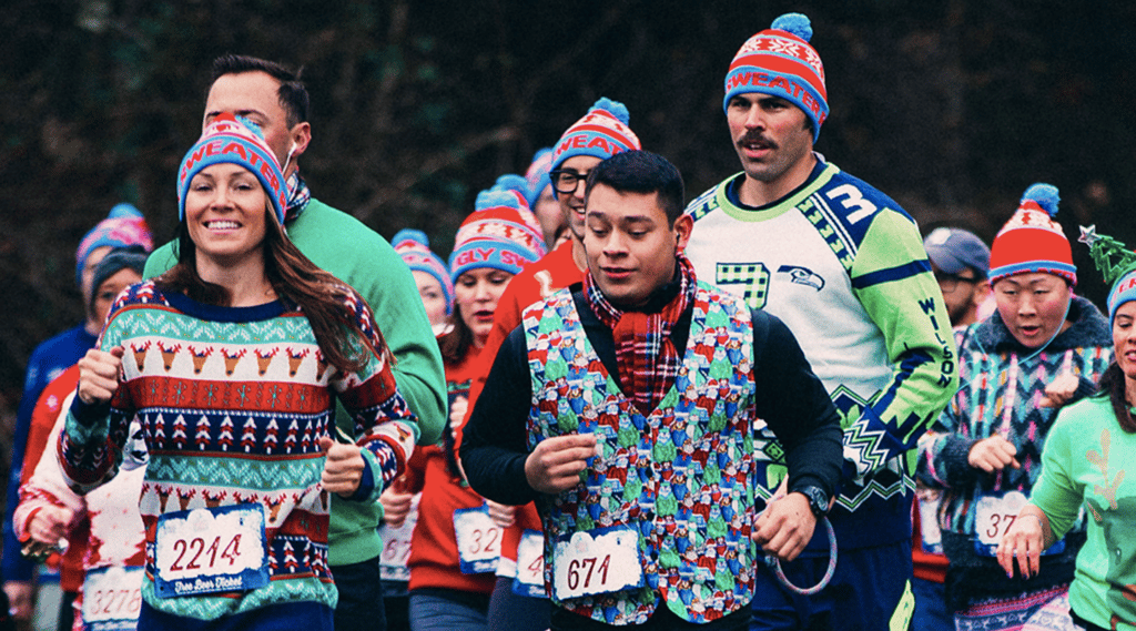 group of people wearing ugly christmas sweaters participating in a beer run