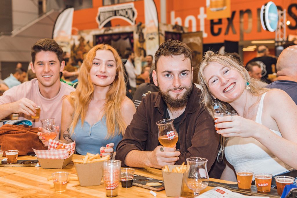 group of friends drinking beer and posing for a photo at craft beer festival