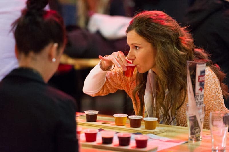 woman drinking craft beer from tasting paddle