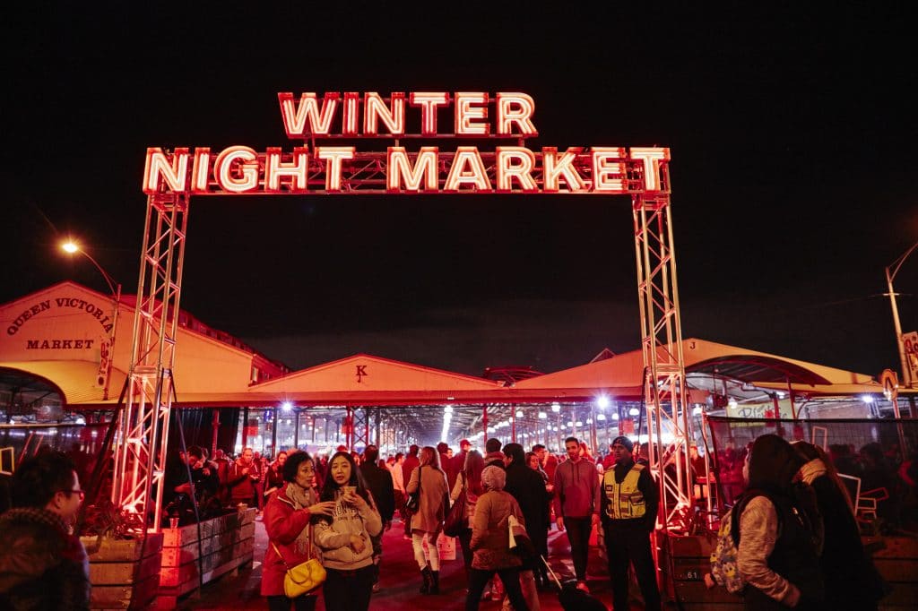 a neon sign above a crowd that says 'Winter Night Market'