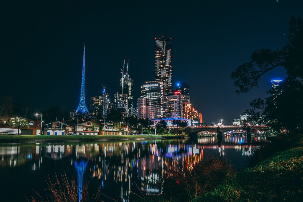 Melbourne's city skyline at night, reflecting in river water