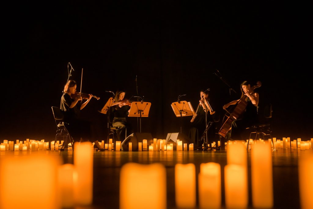 quartet on stage performing amongst candles