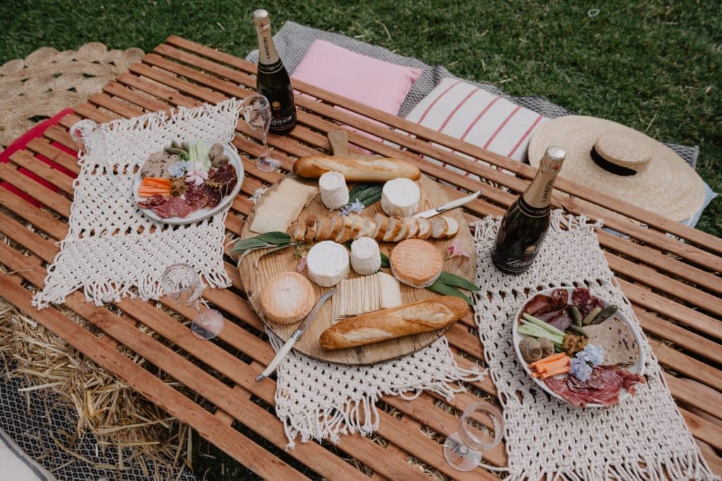 a picnic spread, with crackers, fruit, baguette, champagne and more