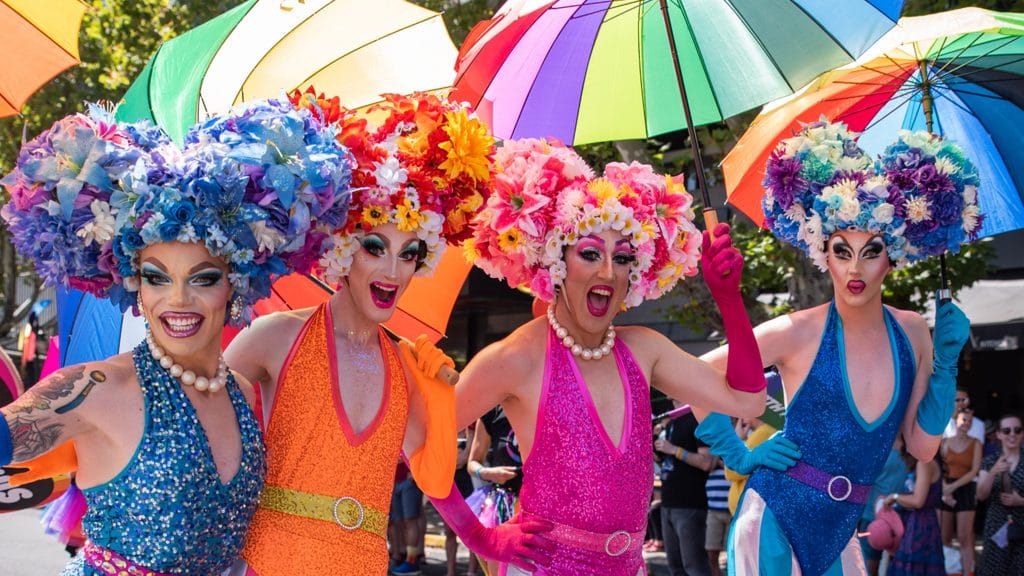 Four drag queens with rainbow umbrellas walking for Pride March as part of Midsumma Festival