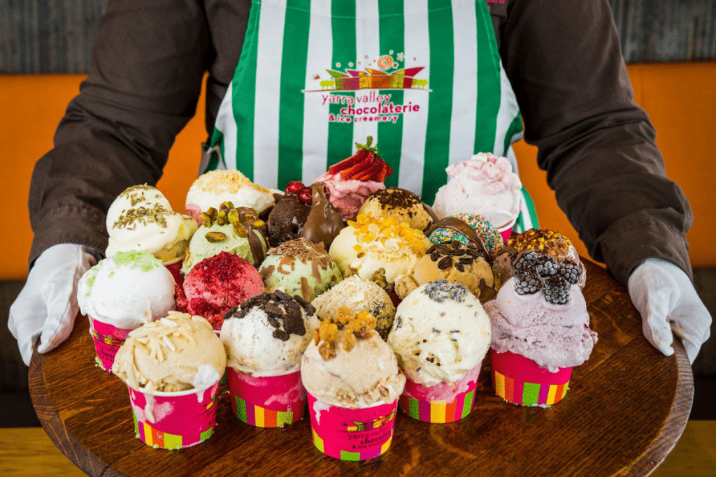 hands holding a wide variety of ice cream flavours in cups on a tray for the ice cream festival