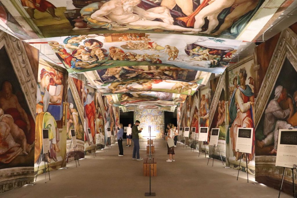people looking at high def photos of sistine chapel exhibition