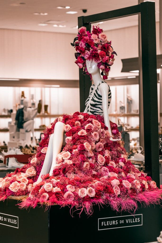 a sitting mannequin, legs crossed, with pink and red flowers for a skirt
