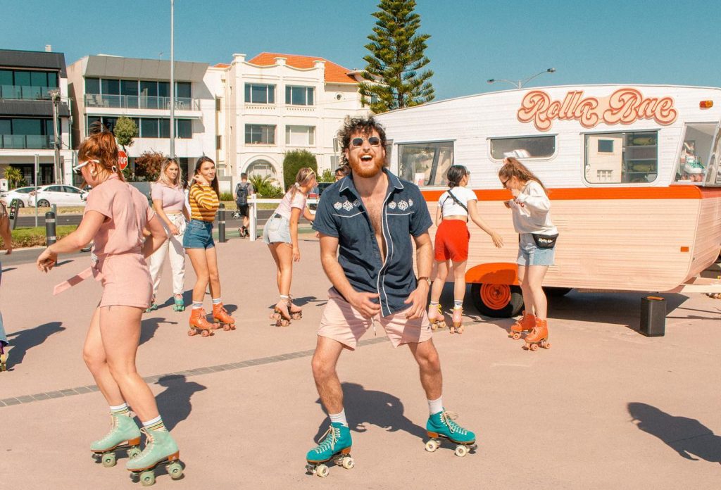 a group of people moving on their roller skates in front of a caravan that says Rolla Bae