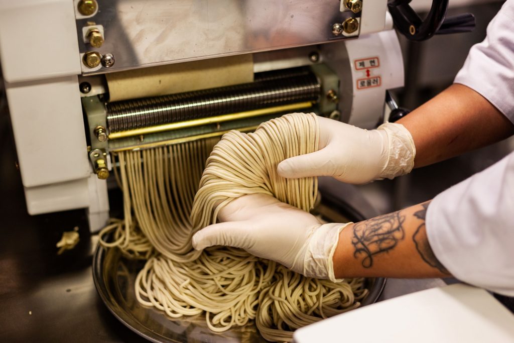 chef's hands holding handmade noodles for Paik's Noodle