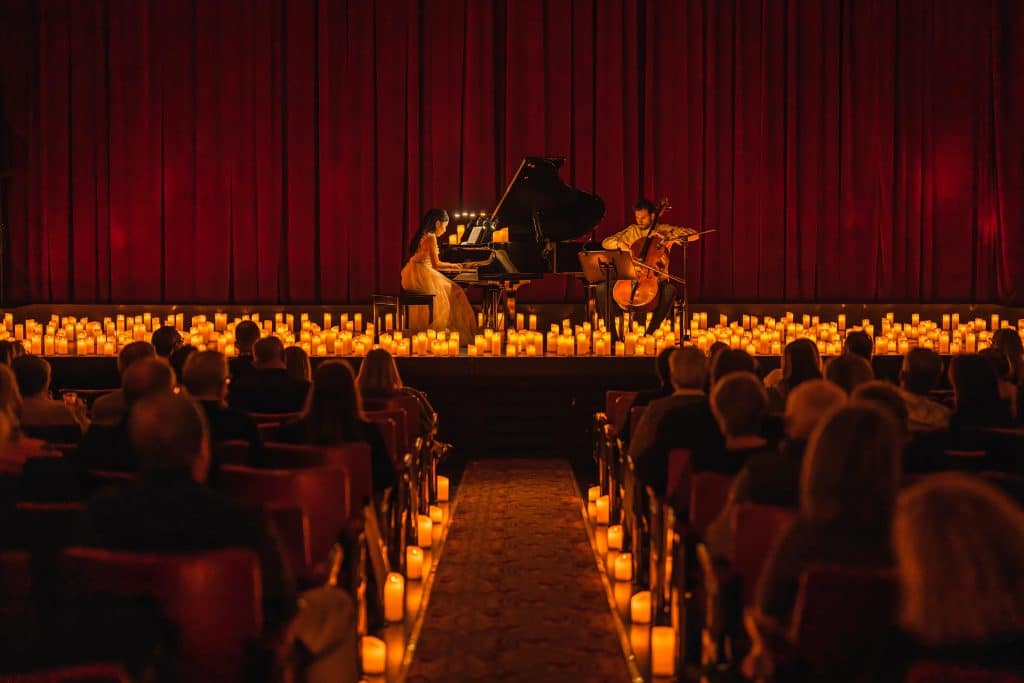 pianist and cellist on theatre stage performing surrounded by candlelight