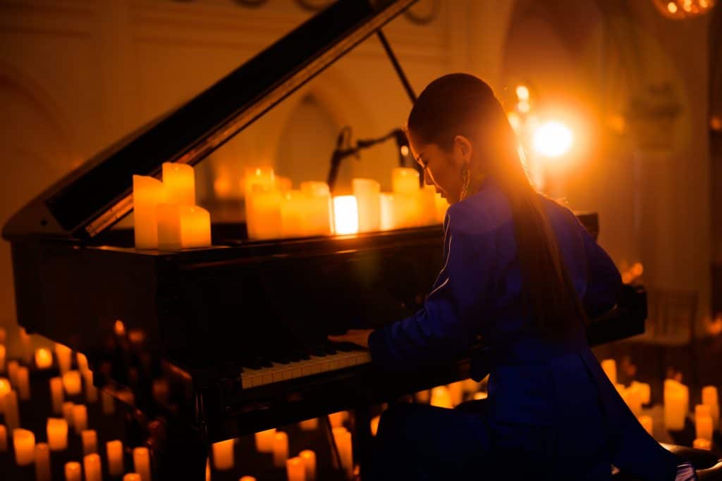 pianist at piano playing while surrounded by candles