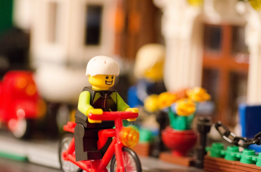 lego minifigure riding red bike on streetscape