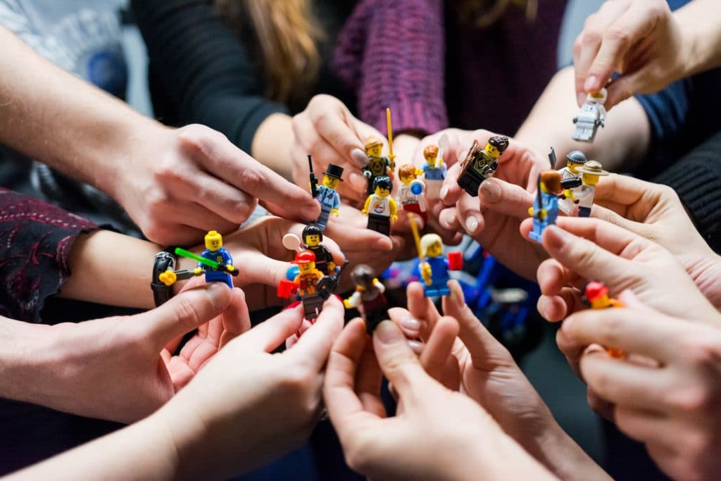 hands in middle of a circle holding lego figurines