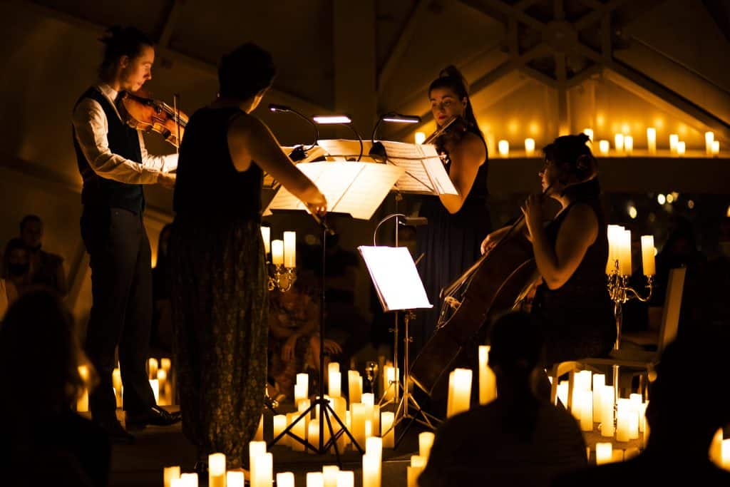 string quartet performing surrounded by candles at candlelight concert