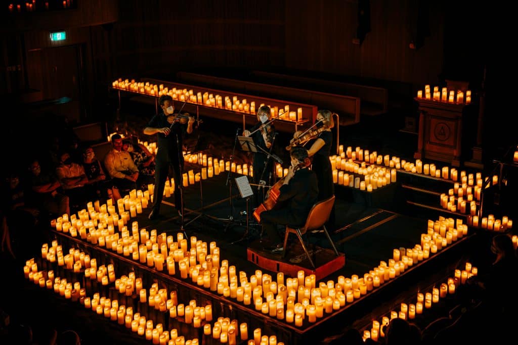 candlelight concert with string quartet performing on stage surrounded by candles