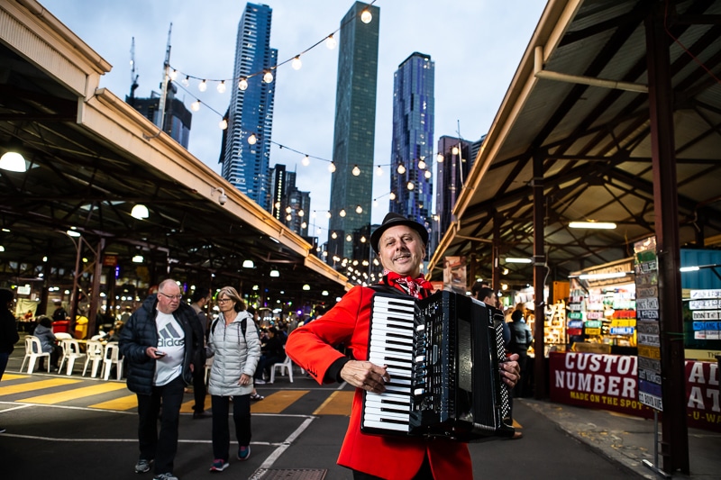 a man playing a piano accordion in the laneway of Queen Victoria Market