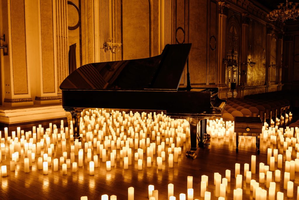 open grand piano surrounded by candles at candlelight concert