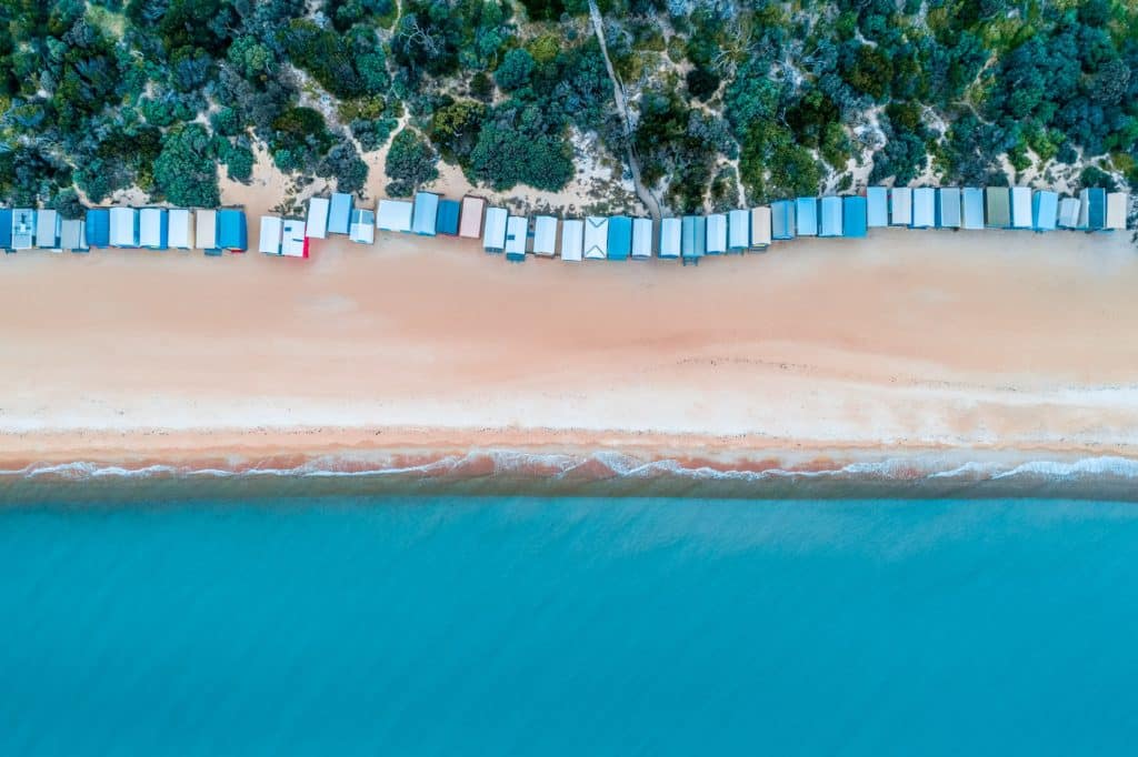 birds eye view of mt martha beach in melbourne/mornington peninsula, showing colourful bathing boxes, green reserves, golden sand, beautiful blue water