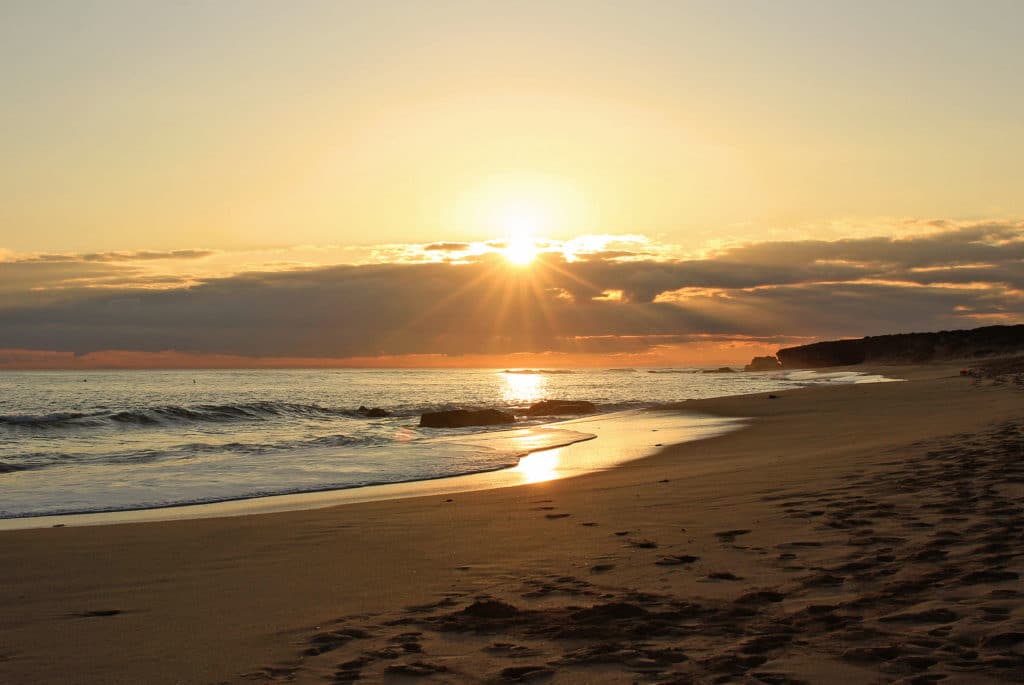 gunnamatta beach of the mornington peninsula, melbourne, at sunset, long open stretch of golden sand with waves crashing onto the shoreline