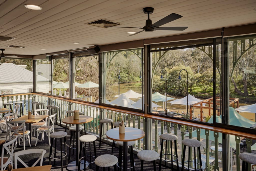 tables and chairs on a balcony overlooking river views