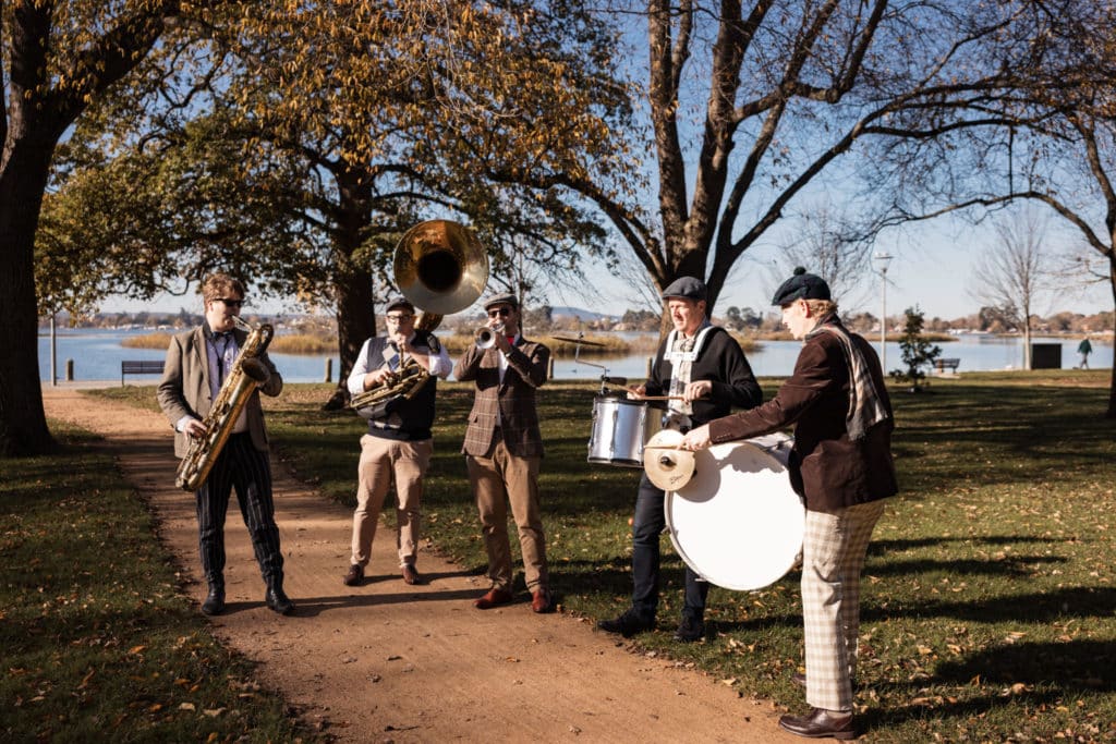 band members in vintage clothing playing instruments at the Ballarat Heritage Festival by a lake