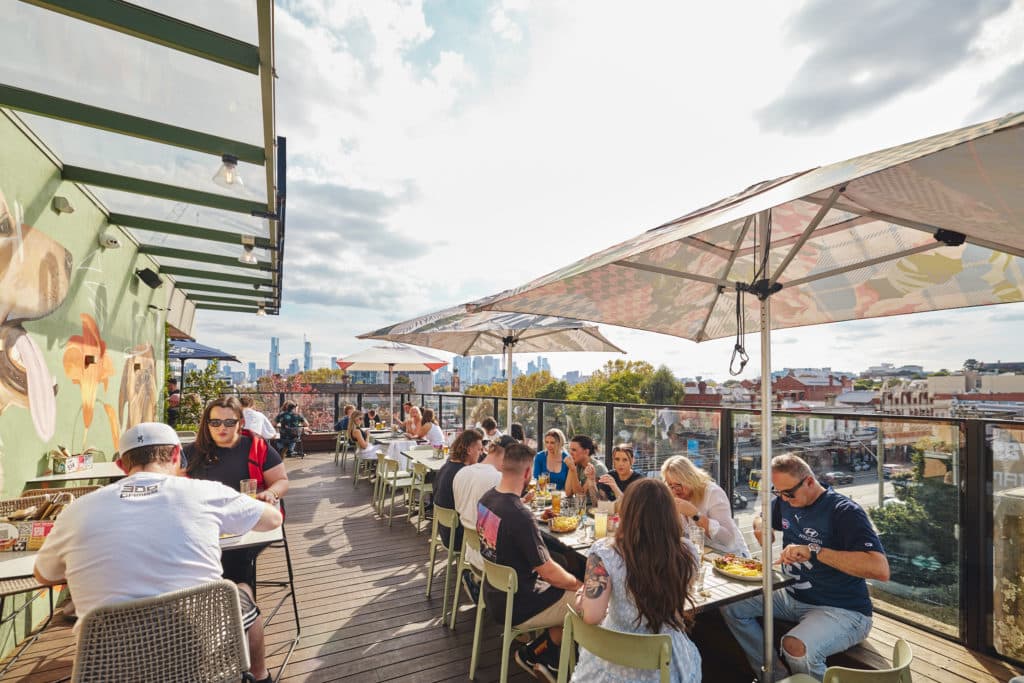 a sunny day with plenty of people dining on the rooftop at Harlow Bar