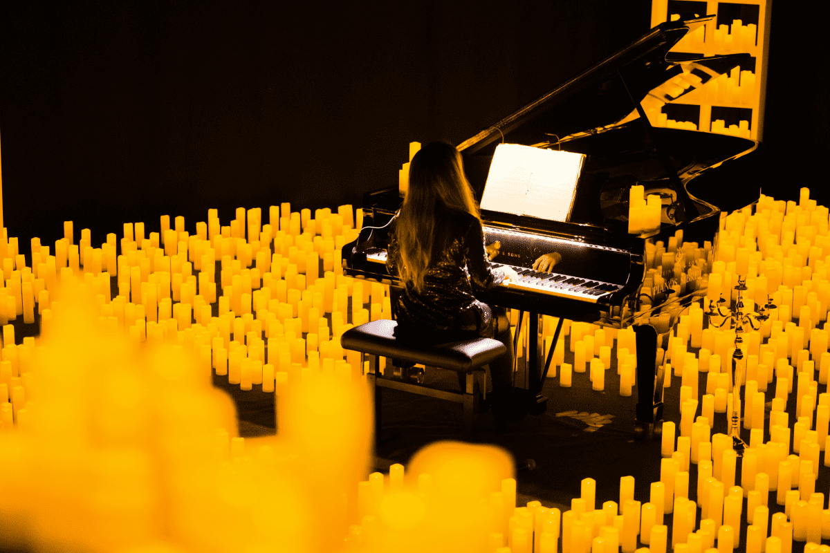 A pianist performs while surrounded by a sea of candles