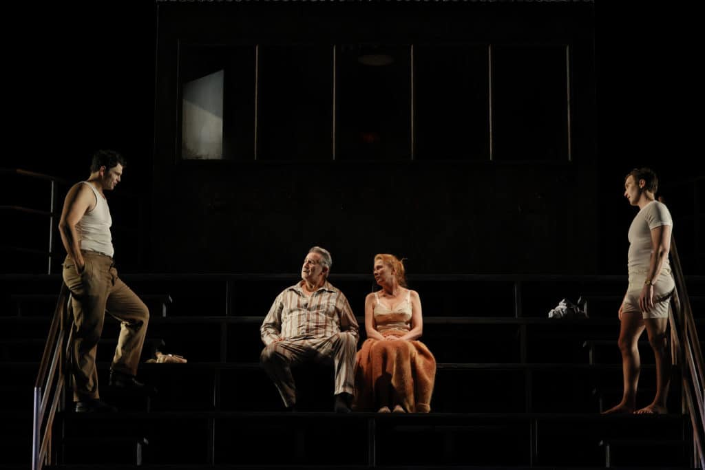 Willy and Linda Loman sitting centre stage, while their sons face each other on opposite sides