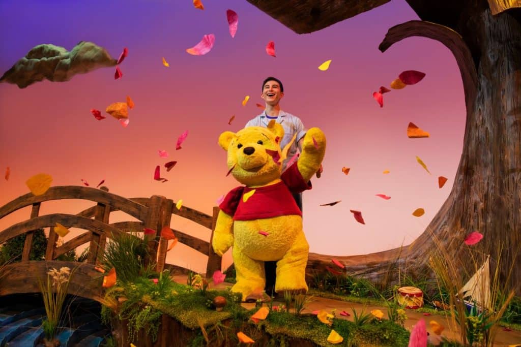 an actor behind a Winnie the Pooh stage puppet