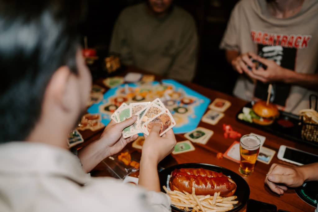 a player holding cards while playing a board game at Fortress Melbourne