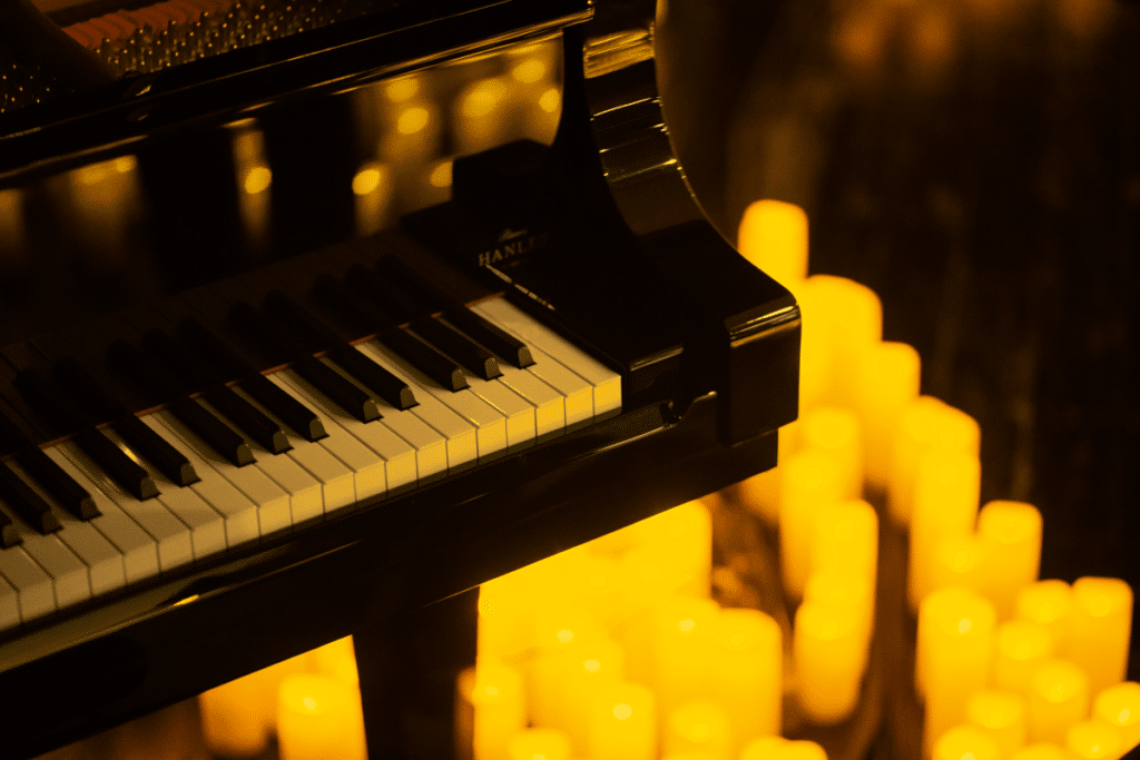 A close up of a grand piano with blurry candles in the background