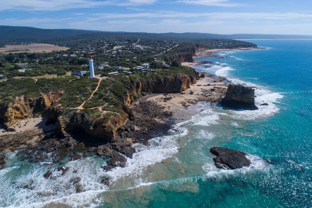 Aerial view of a lighthouse with the town of Aireys Inlet behind, one of the Top Tourism Town award winners in Victoria
