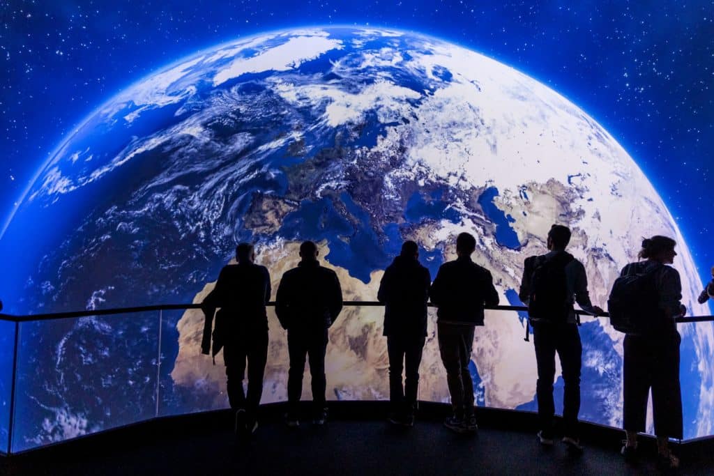 silhouettes of people admiring a massive projection of planet Earth at the BBC Earth Experience