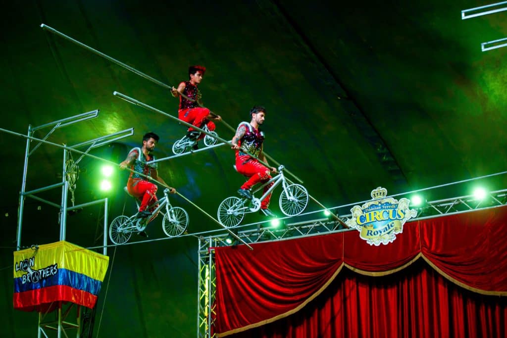 three people riding bikes on a tightrope 