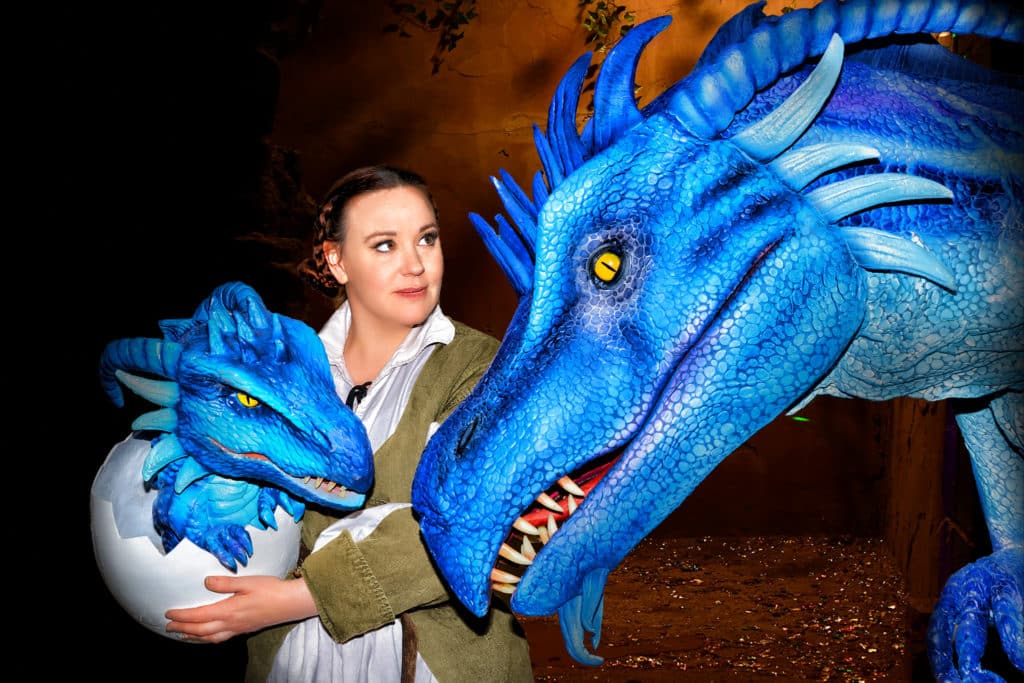 a woman with a blue baby dragon next to a large blue dragon head
