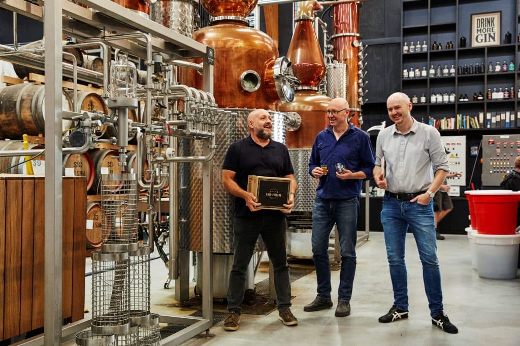 three men standing inside the distillery of Four Pillars Gin