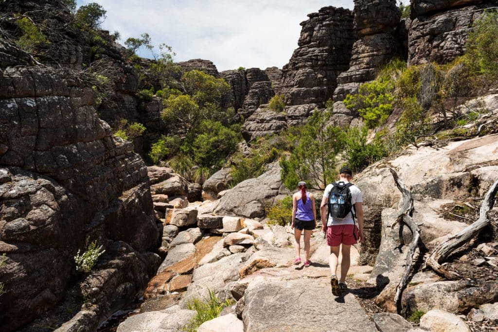 two people hiking along a rocky path at the bottom of the Grand Canyon in the Grampians
